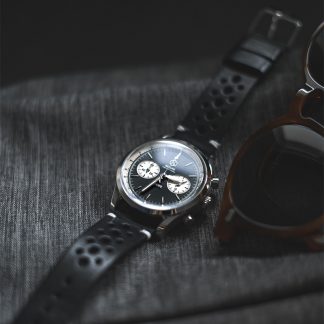 Black leather traditional wrist watch on black wood surface.